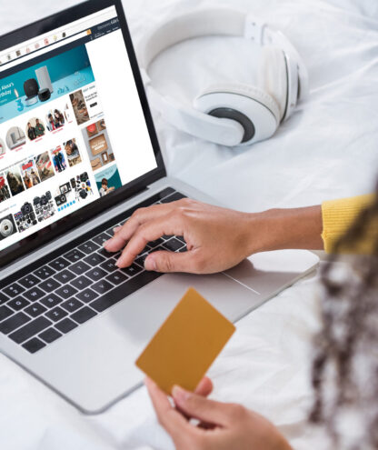 cropped image of woman holding credit card and using laptop with amazon  on screen