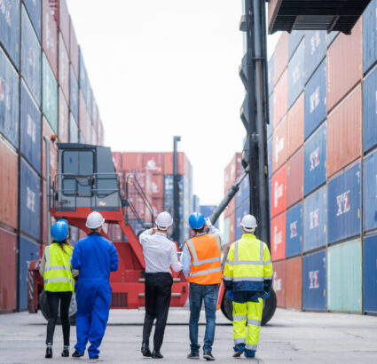 Manager and professional container yard workers checking stock for loading in the container yard warehouse,Logistic shipping yard business.